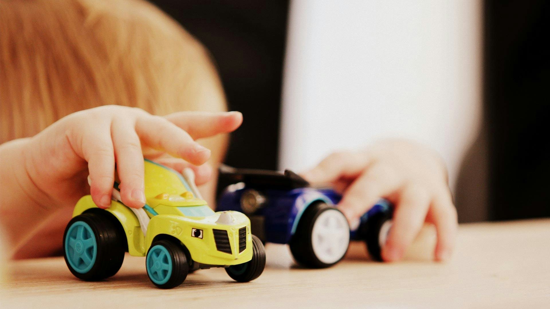 Child Playing with Yellow and Blue Toy Trucks